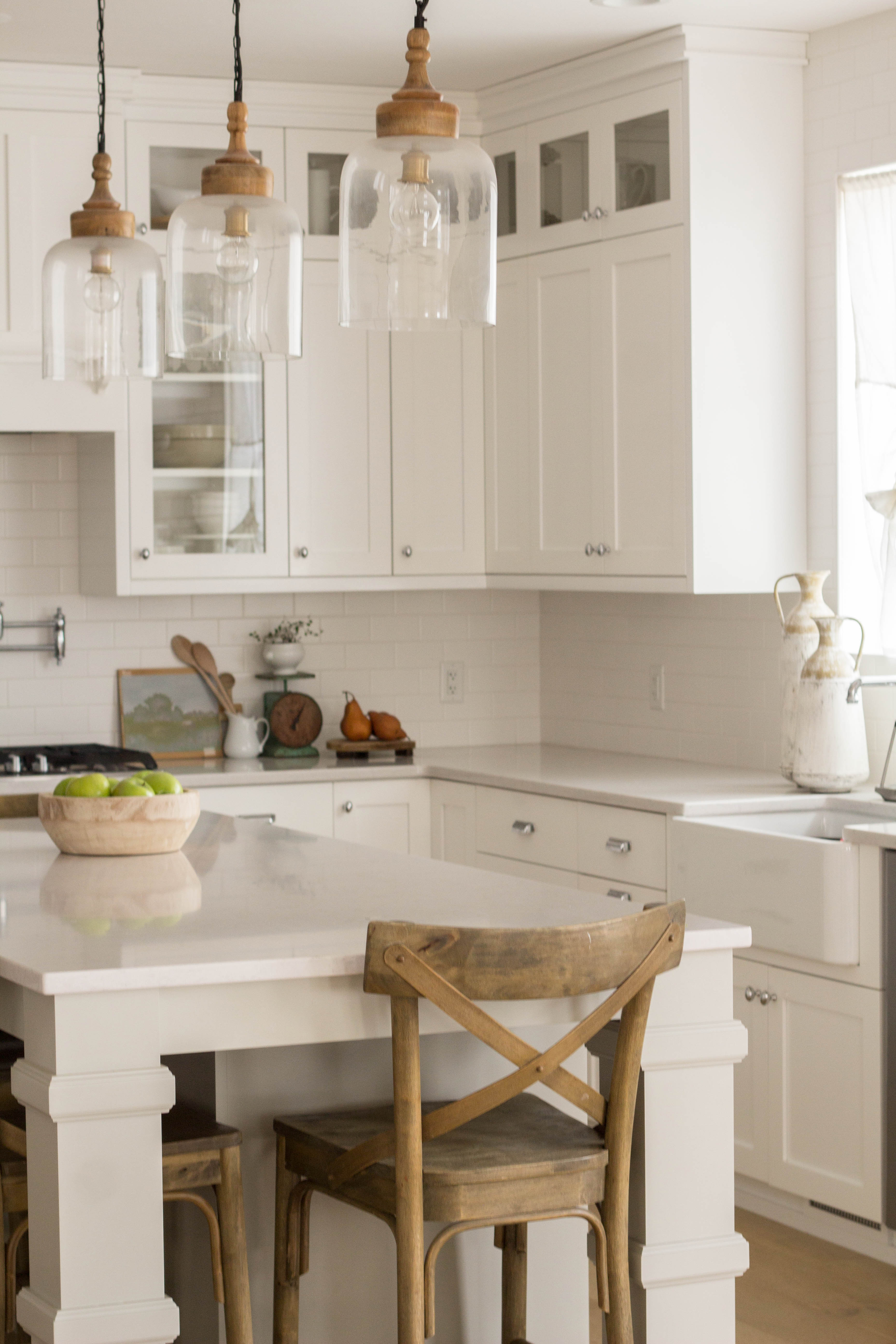 a white kitchen with a bowl of apples sitting on the island countertop