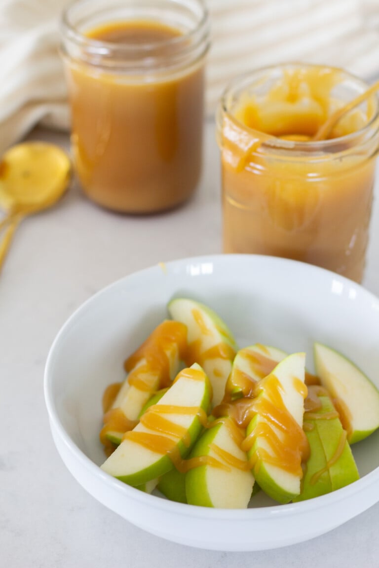 Homemade caramel sauce drizzled on a bowl on sliced apples.